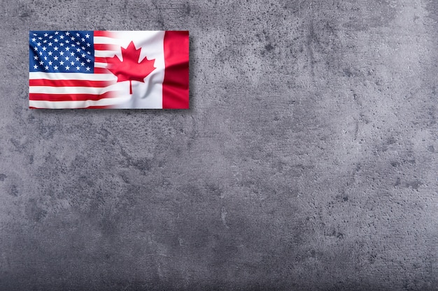 USA flag and Canada flag on concrete background.