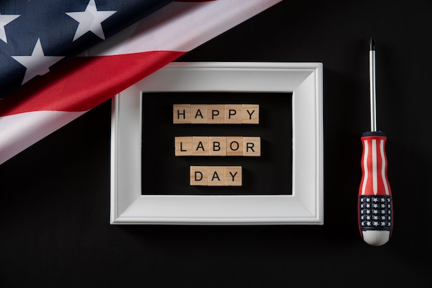 USA flag and HAPPY LABOR DAY wooden text in white photo frame on dark background