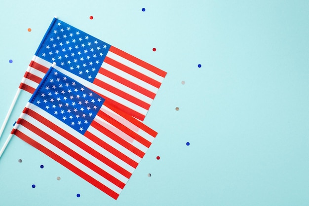 USA Independence Day concept Top view photo of two national flags and confetti on isolated pastel blue background