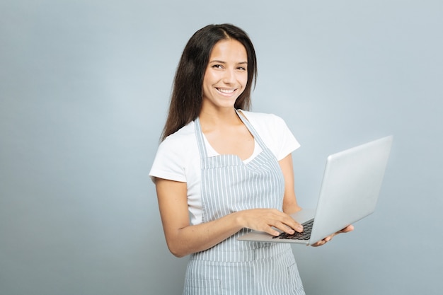 Use computer. Attractive woman expressing positivity while posing on camera and showing her friendly smile