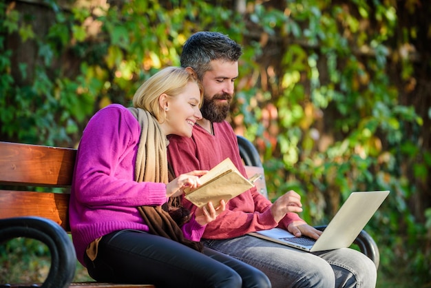 Use digital approach as well as books. Man and woman use different information storage. Couple spend leisure reading. Couple with book and laptop search information. Information source concept.