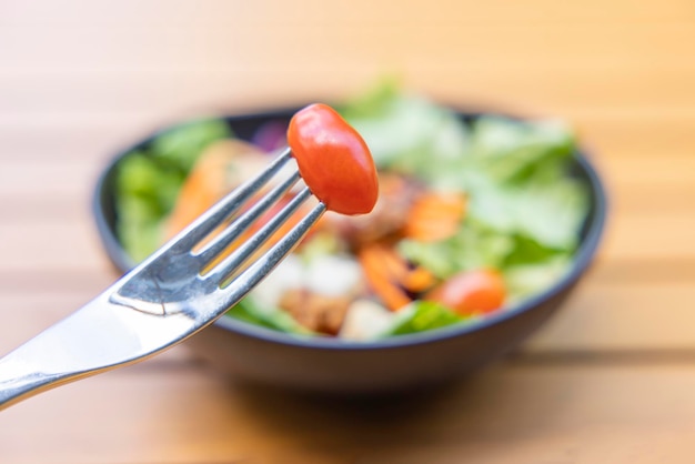 Use a fork a tomato skewer in the foreground and a salad in the background Breakfast salad