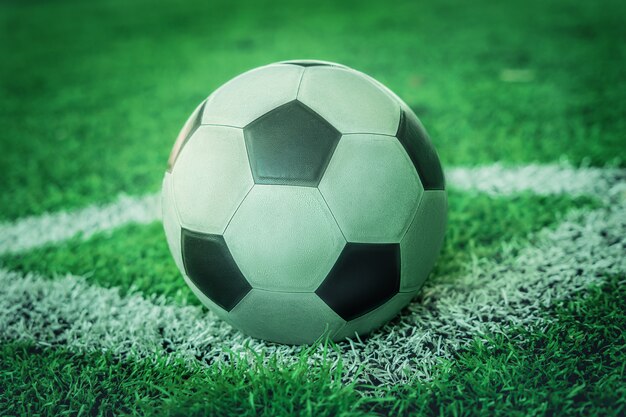 Used Classic black and white soccer ball on football corner marking field with no people.