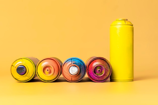 Used colorful spray cans isolated on orange background b