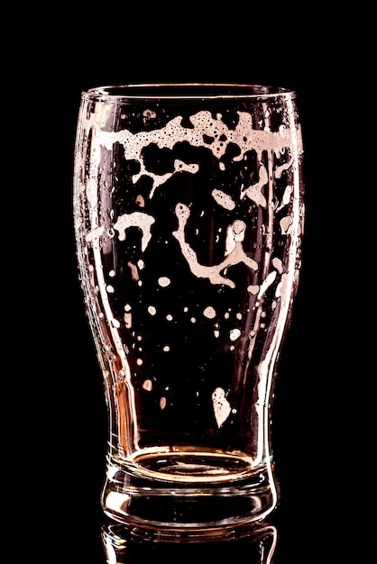 Used empty Beer Glass with drops on black. Beer bubbles closeup