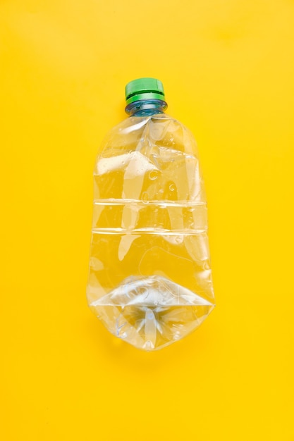 Used plastic bottle of water with caps on yellow background