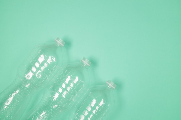 Used plastic bottles lie chaotically on green background for recycling. Top view, copy space.