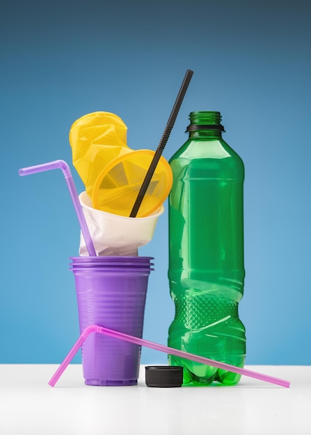 Used plastic. Disposable cups, drinking straws and a bottle. The concept of ecology and recycling.