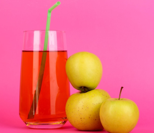 Useful apple juice with apples around on pink background