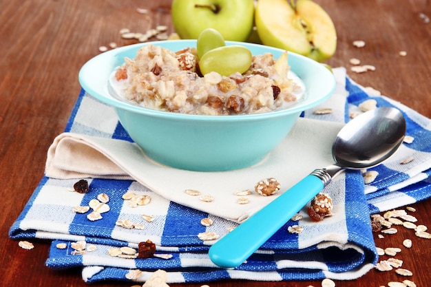 Useful oatmeal in bowl with fruit on wooden table closeup