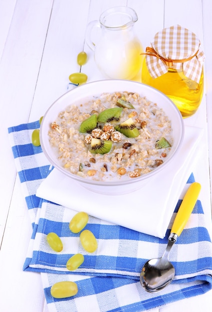 Useful oatmeal in bowl with fruit on wooden table closeup