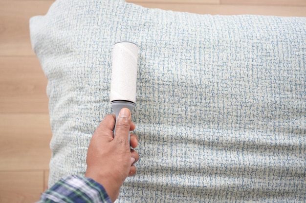 Photo using an adhesive roller to remove lint and fluff from a bed