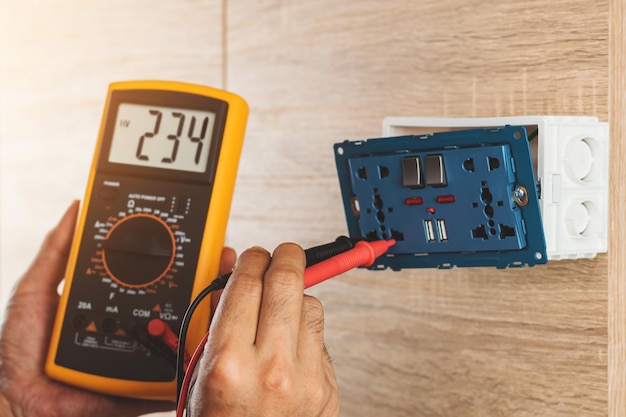 Using a digital meter to measure the voltage at an electric outlet socket box isolated on white background