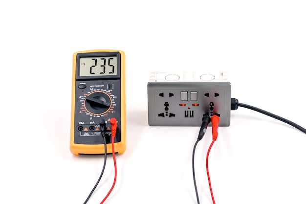 Using a digital meter to measure the voltage at a electric socket box on white background.