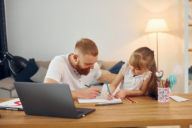 Using laptop Father with his little daughter is at home together