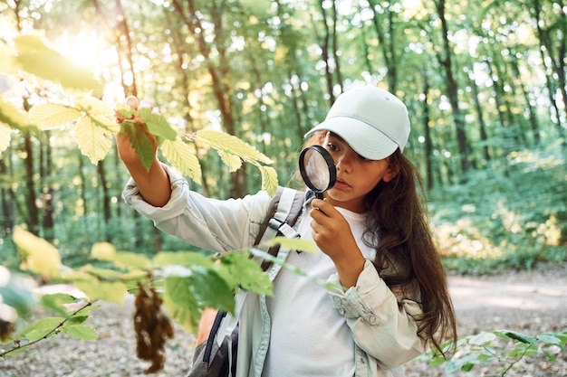 Photo using magnifying glass girl is in the forest at summer day time discovering new places