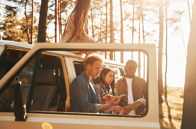 Using map Group of young people is traveling together in the forest at daytime