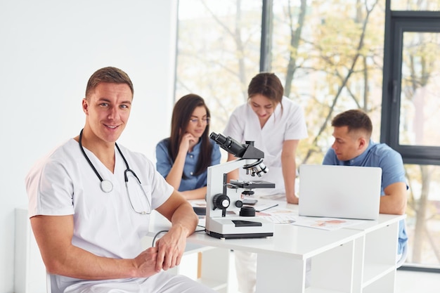 Photo using microscope group of young doctors is working together in the modern office