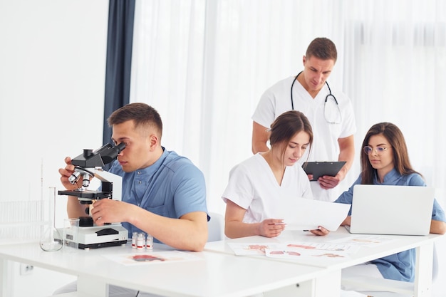 Photo using microscope group of young doctors is working together in the modern office