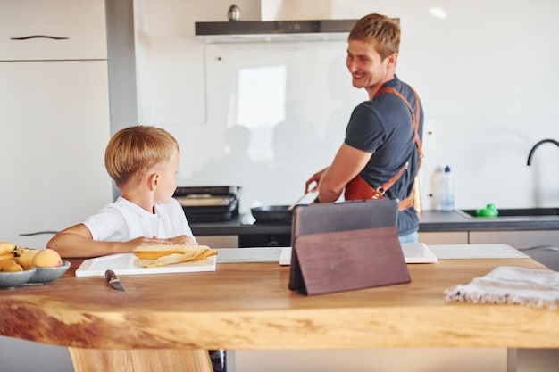 Using tablet to learn how to cook Father and son is indoors at home together