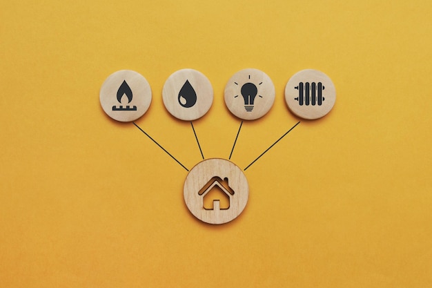 Utility icons on wooden mugs and a house nearby. A symbol of the necessary services in the house