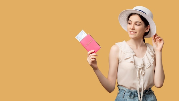 Vacation aspiration Holiday trip Travel agency Smiling curious woman in summer outfit looking at foreign passport with tickets isolated on beige copy space Advertising background