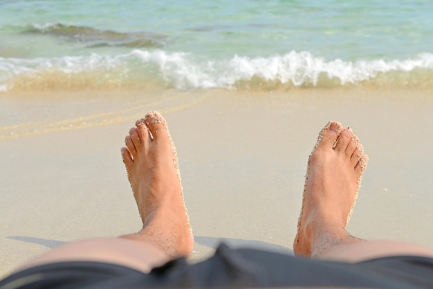 Vacation holidays Man Bare Feet relaxing on the beach Wave and sand texture