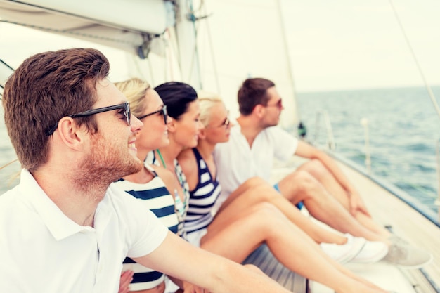 vacation, travel, sea, friendship and people concept - smiling friends sitting on yacht deck