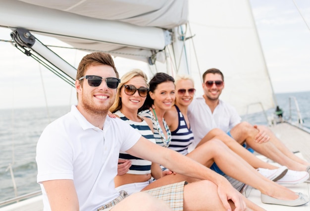 vacation, travel, sea, friendship and people concept - smiling friends sitting on yacht deck