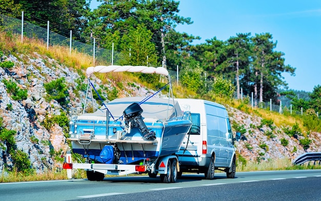 Vacation trip with Caravan Car and trailer with yacht or boat on road of Italy. Camper and Summer drive on highway. Holiday journey in rv motorhome for recreation. Motor home motion ride.