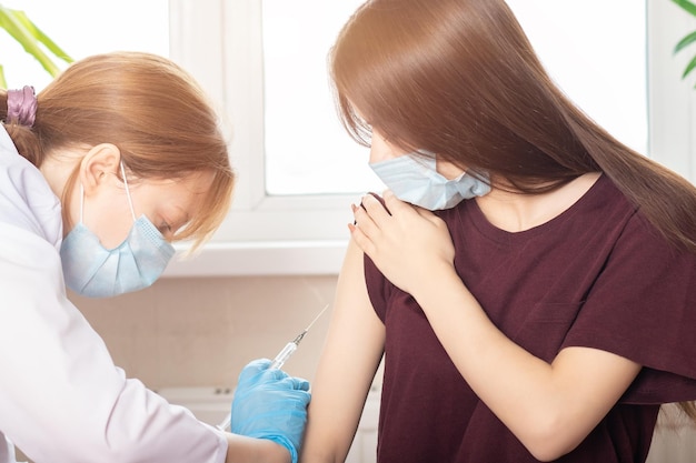 Vaccination of adolescents in medical clinics schools a doctor giving an injection to a girl in a hospital a nurse holding a syringe before administering a dose of coronavirus vaccine from covid19