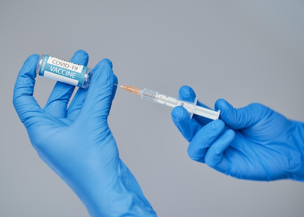 Vaccination against covid a doctor in blue gloves holds a syringe and an ampule with a vaccine