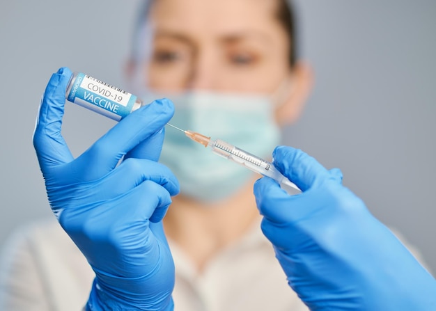 Vaccination against covid a doctor in blue gloves holds a syringe and an ampule with a vaccine