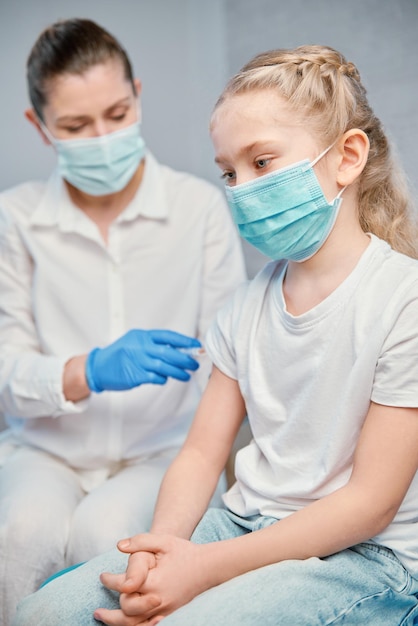 Vaccination of children A woman doctor makes injection with a syringe of a vaccine to a teenager