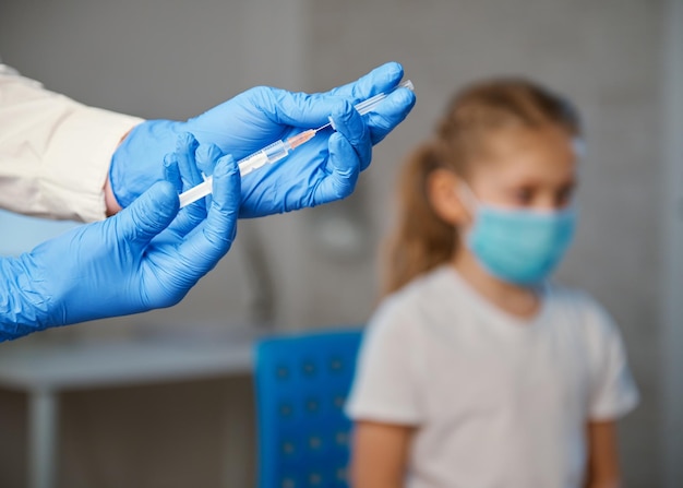 Vaccination of children A woman doctor makes injection with a syringe of a vaccine to a teenager