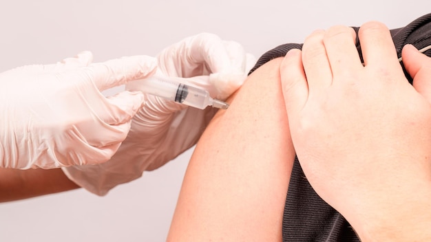 Vaccination close up injection of vaccine in hand doctor in white gloves