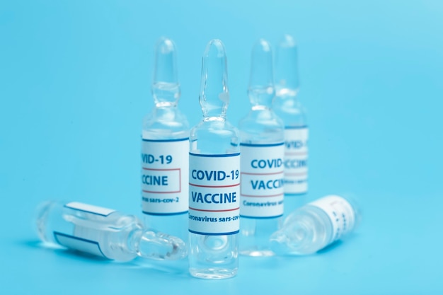 Vaccine against COVID-19. Glass medical vials with liquid. Ampoules with coronavirus vaccine on a medical glass table