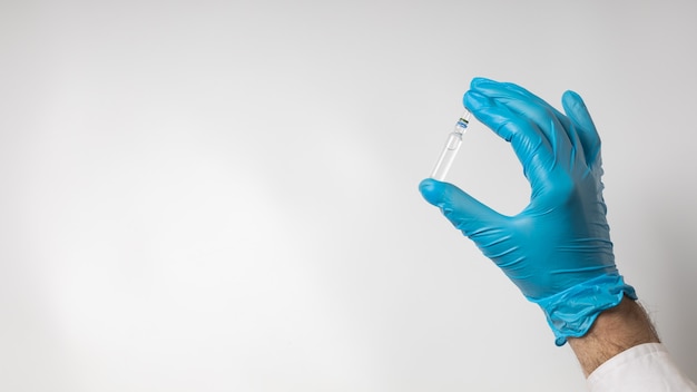 Vaccine ampoule in hand in a medical glove