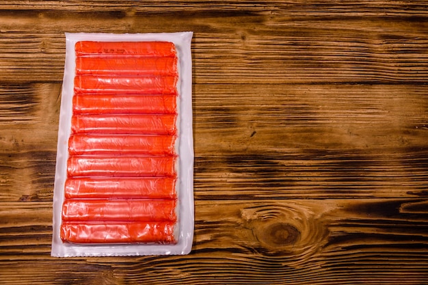 Vacuum pack of crab sticks on a wooden table. Top view