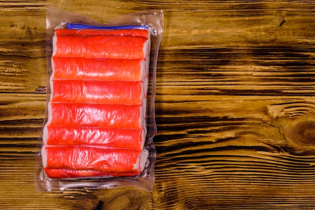 Vacuum pack of crab sticks on a wooden table Top view