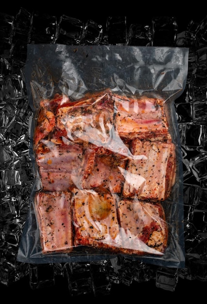 Vacuumpacked meat on dark ice background pork ribs SemifinishedTop view