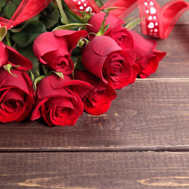 Valentine background of  red roses and ribbon on wood