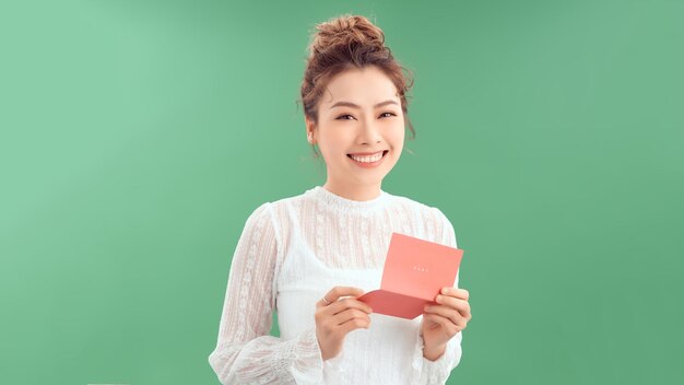 Valentine card from him Beautiful young woman holding valentine card and smiling while standing isolated on green