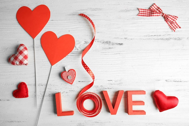 Valentine concept Inscription love with hearts and card on wooden table background