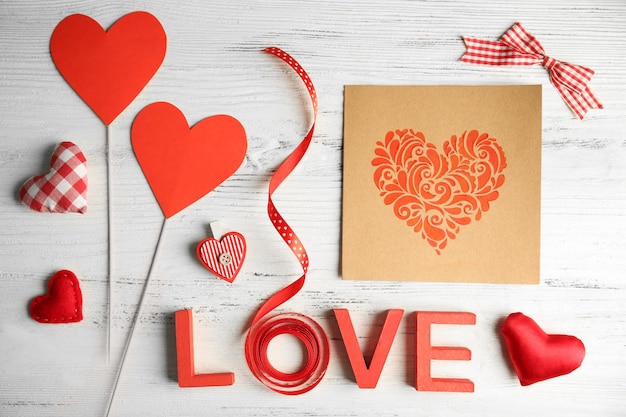 Valentine concept Inscription love with hearts and card on wooden table background