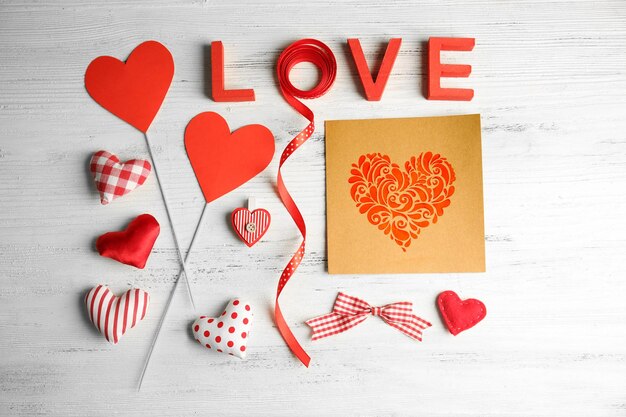 Valentine concept Inscription love with hearts and card on wooden table background