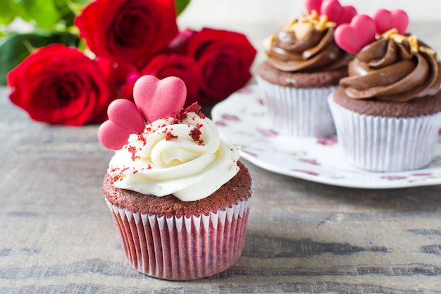 Valentine cupcakes decorated with sugar heart and roses surface on wooden table