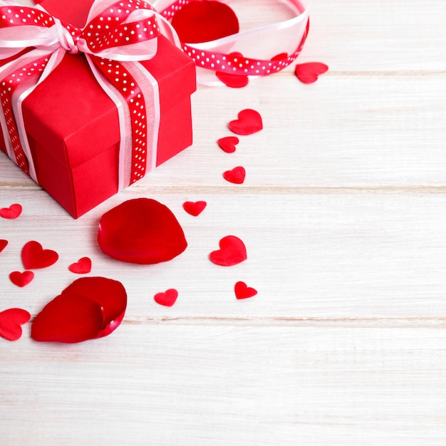 Valentine day background of gift box and rose petals on white wood