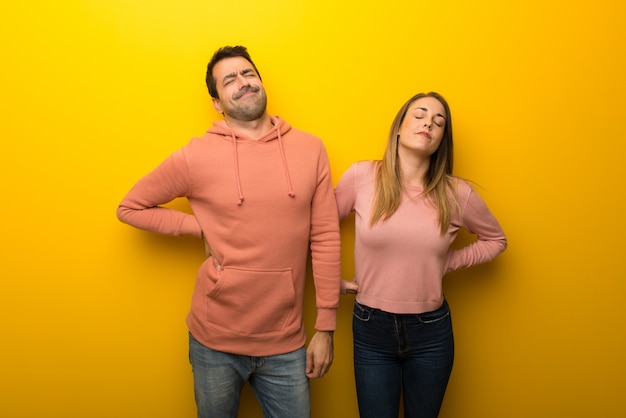 In valentine day Group of two people on yellow background suffering from backache for having made an effort