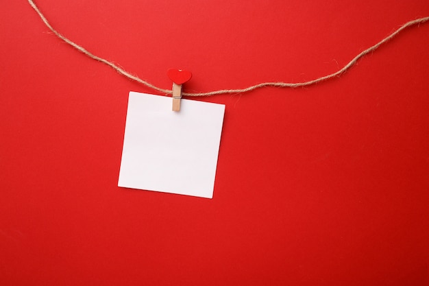 Valentine day minimalistic composition. Paper note on a clothespin with a heart on a rope. Top view, mock up.